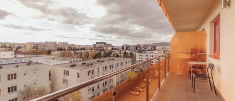 Un balcon donnant sur un paysage urbain, avec une table et des chaises.