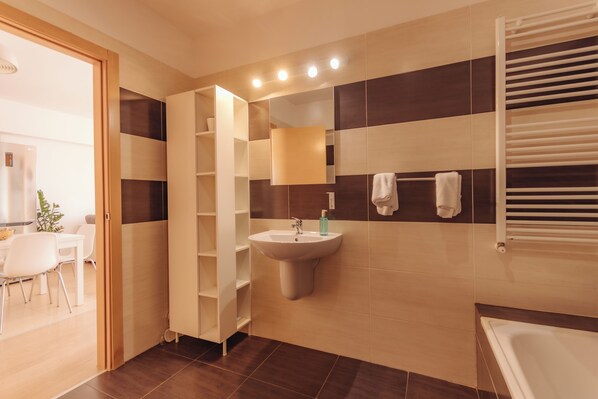 A modern bathroom with a sink, mirror, towel rack, and a shower area.