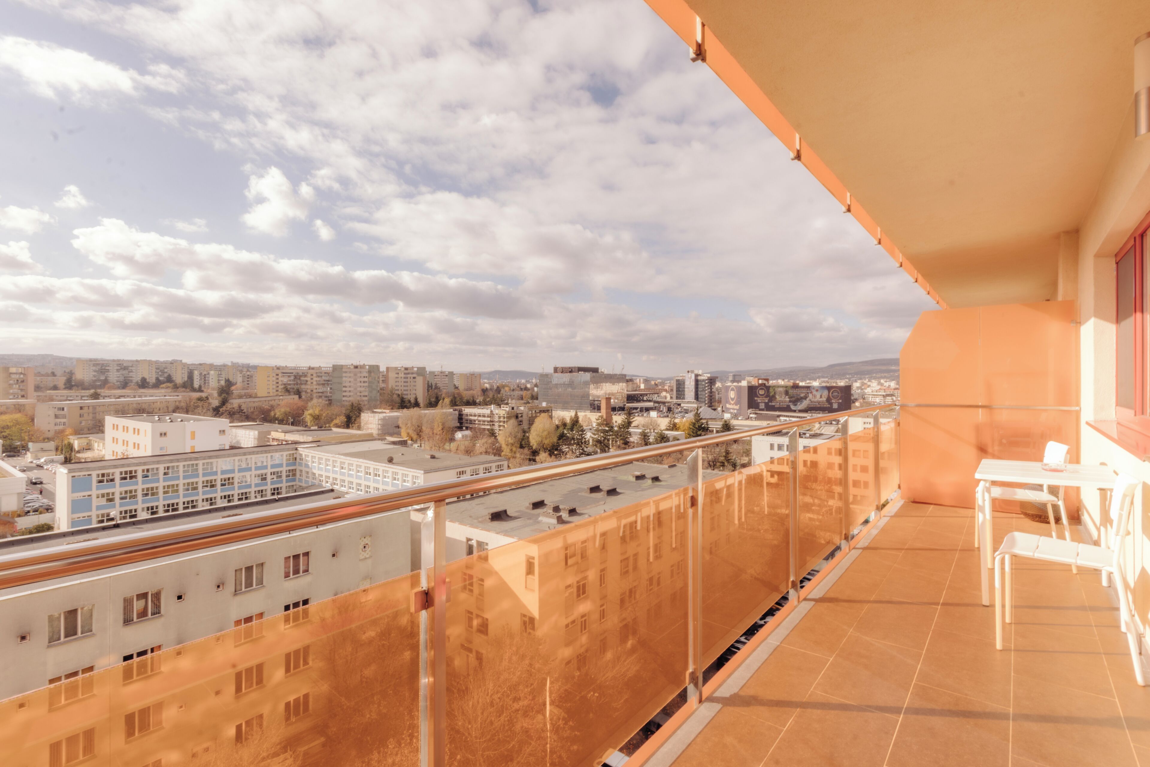 A balcony with a view of a cityscape, including buildings and a road.