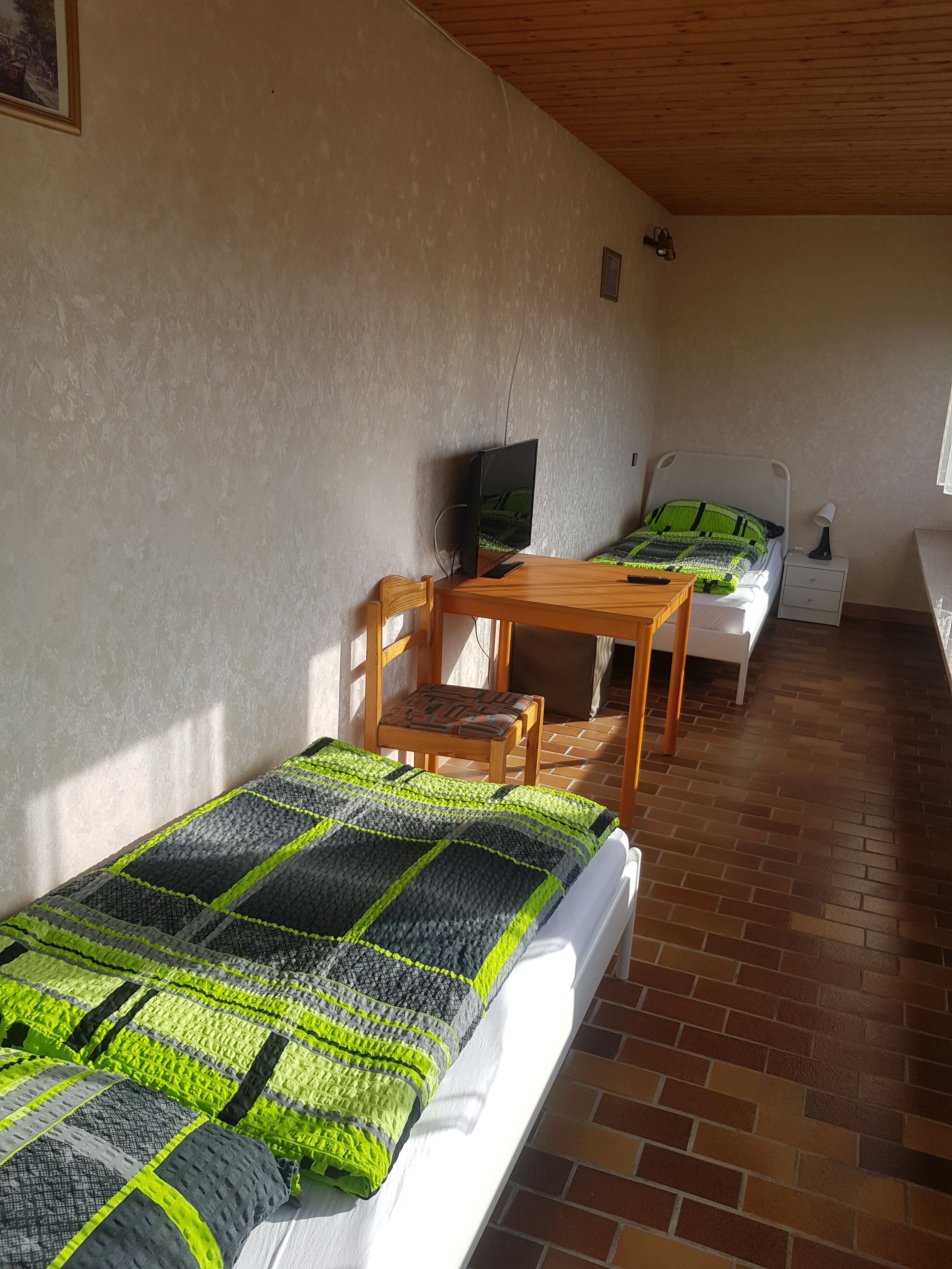 Una habitación con dos camas, un escritorio y un televisor.