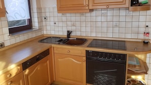 A kitchen with wooden cabinets, a dishwasher, an oven, and a sink.