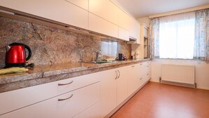 A kitchen with white cabinets, a granite countertop, and a red kettle. - Ferienhaus mit Pool st Koloman (St. Koloman)