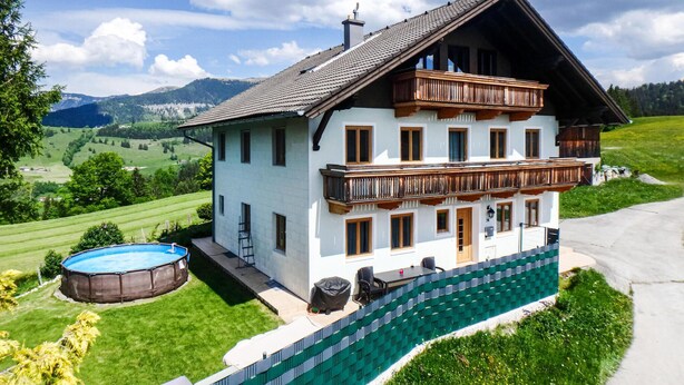 A two-story house with a balcony, a swimming pool, and a green fence. - Ferienhaus mit Pool st Koloman (St. Koloman)