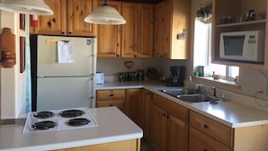 A kitchen with wooden cabinets, a white refrigerator, a stove, a microwave, and a sink. - Fish the San Juan River (Pagosa Springs)