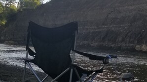 A camping chair on a rocky shore with a river and mountains in the background. - Fish the San Juan River (Pagosa Springs)