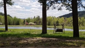 A serene outdoor setting with a pond, a wooden swing, and a bench. - Fish the San Juan River (Pagosa Springs)