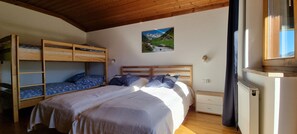 A bedroom with a bunk bed, a single bed, a wooden headboard, a nightstand, a drawer, a radiator, and a window. - Spacious, privacy and beautiful unobstructed view of the mountains and valley (Stuhlfelden)
