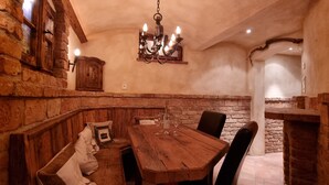 A rustic dining area with a wooden table and benches, stone walls, and a chandelier. - Spacious, privacy and beautiful unobstructed view of the mountains and valley (Stuhlfelden)