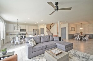A spacious living room with a grey sectional sofa, a wooden coffee table, and a ceiling fan.