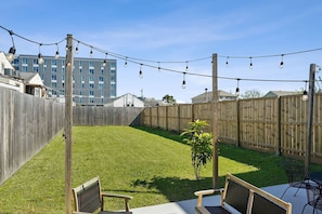 Un jardin avec une clôture en bois, une pelouse verdoyante et une guirlande de guirlandes lumineuses.