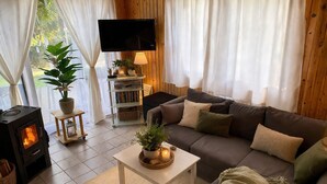 A cozy living room with a fireplace, a sofa, a TV, and a bookshelf.