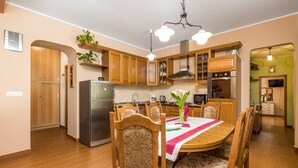 A modern kitchen with wooden cabinets, a stainless steel refrigerator, and a dining area with a wooden table and chairs. - Nice home in Veli Brgud (Veli Brgud)