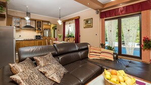 A cozy living room with a leather sofa, a dining table, and a kitchen in the background. - Nice home in Veli Brgud (Veli Brgud)