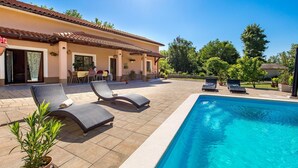 A poolside area with lounge chairs, a dining table, and potted plants. - Nice home in Veli Brgud (Veli Brgud)