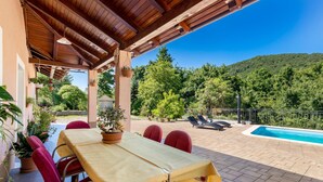 A covered outdoor dining area with a pool and a view of a forested hill. - Nice home in Veli Brgud (Veli Brgud)
