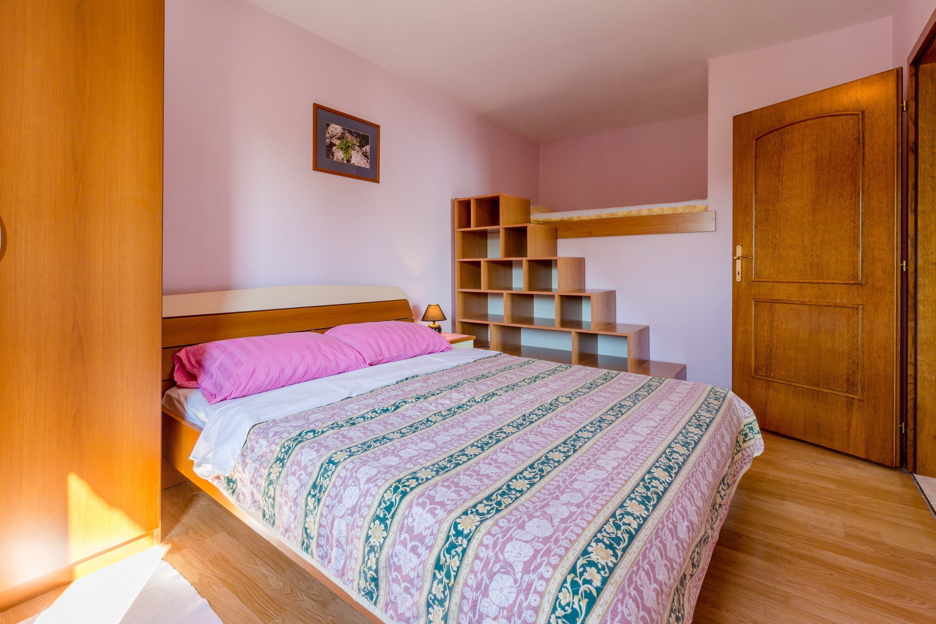 Una camera da letto con un letto, una scaffalatura in legno e una porta.