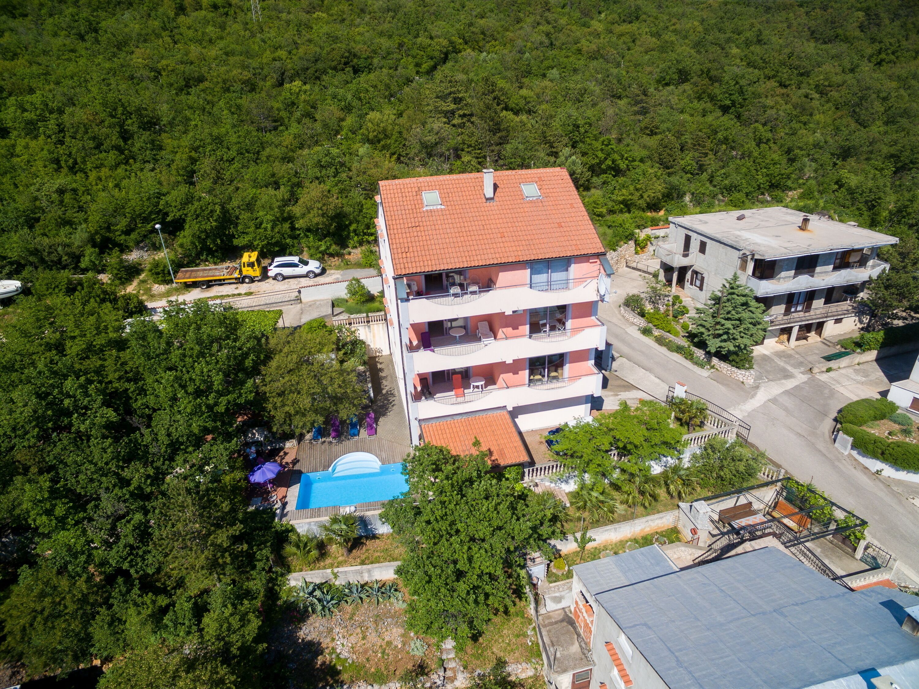 Un edificio de varios pisos con balcones, piscina y zona de estacionamiento.