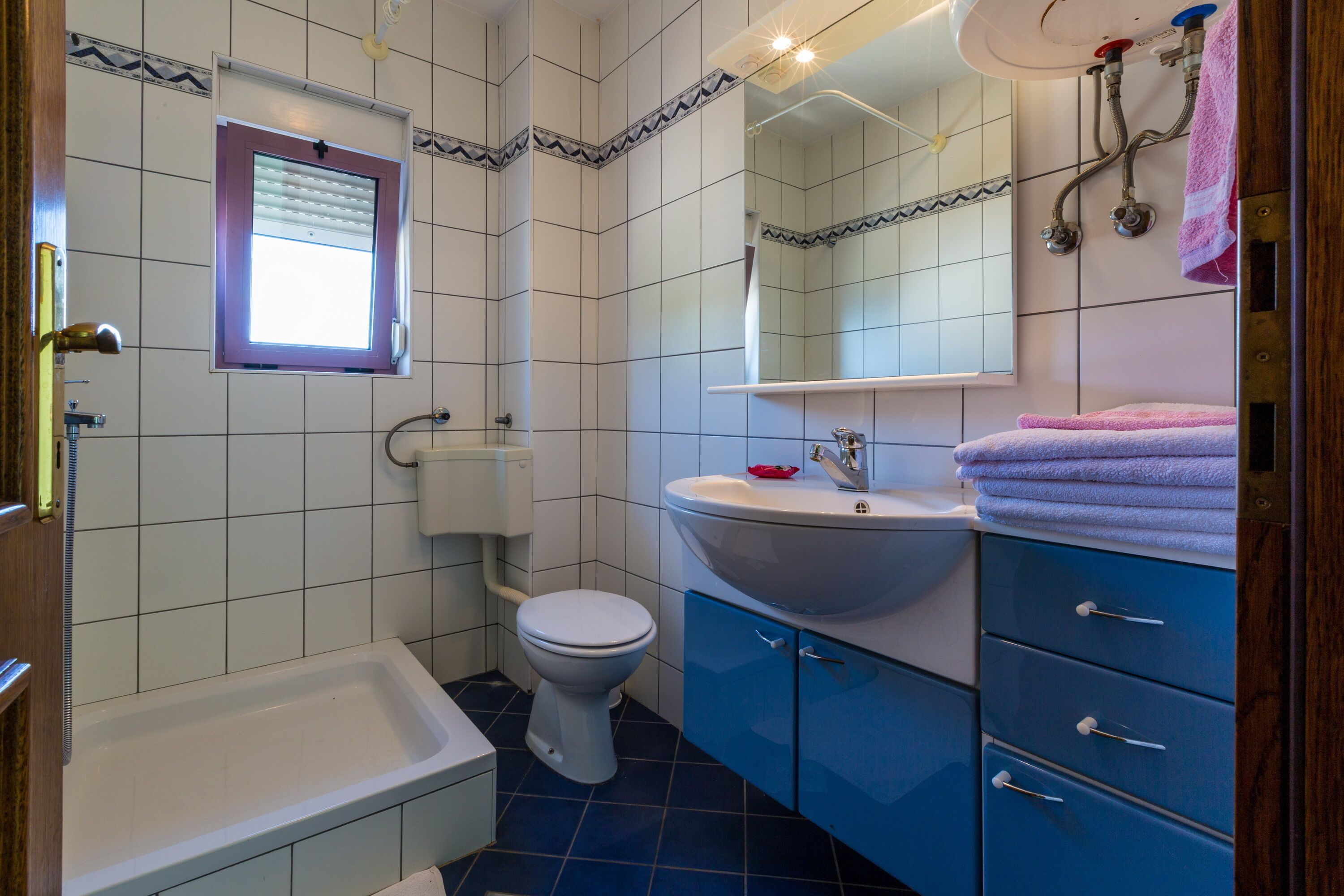 Une salle de bain avec des toilettes blanches, un lavabo blanc et un meuble bleu.