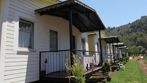 Filetta di cabine bianche con ringhiere nere e portico coperto, immerse in un prato curato e alberi.