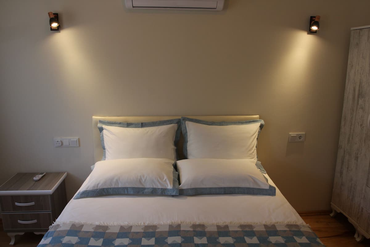 A bedroom with a bed, bedside tables, and wall-mounted lights.