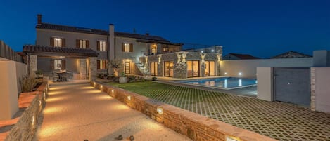 A modern house with a swimming pool, stone pathway, and outdoor seating area.
