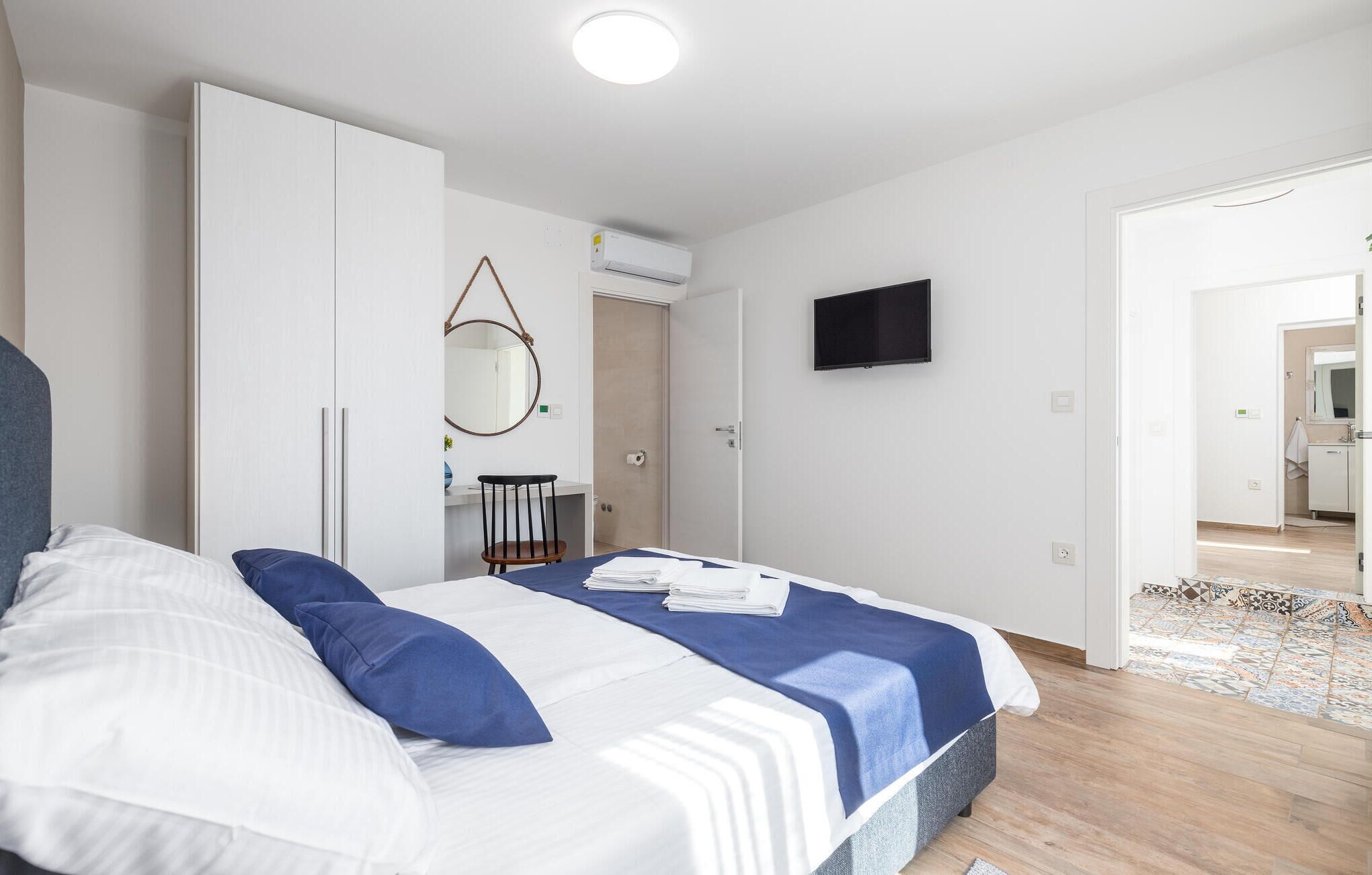 Une chambre à coucher moderne avec un lit, un bureau et un téléviseur.