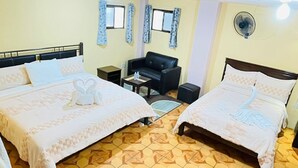 A hotel room with two beds, a sofa, a small table, and a fan. - Hotel Edelmira (Comitan de Dominguez)