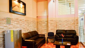 A room with two black leather sofas, a small table with a vase, a refrigerator, and a wall-mounted picture. - Hotel Edelmira (Comitan de Dominguez)