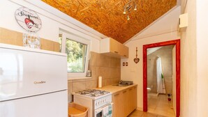 Una cucina compatta con piano cottura a gas, frigorifero e pensili in legno.