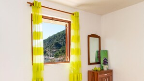 Una stanza con una finestra, tende gialle, un armadietto in legno e uno specchio.