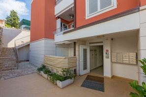Stylish apartment building with a clean design, featuring a balcony and covered outdoor seating area.