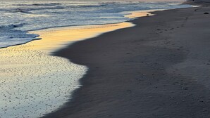 En strand med ett lugnt hav och en solnedgång.