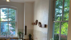 Eine moderne Küche mit Holzschränken, einer Edelstahlspüle und einem großen Fenster mit Blick auf die Nachbarschaft.