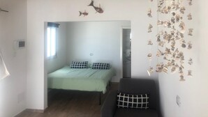 Un dormitorio con una cama, una silla y un adorno de peces en la pared.