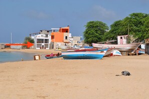 A beach with several boats, a building with multiple stories, and a clear sky. - Casa Tud Dret - luxurious apartments (Boa Vista)