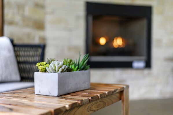 Una sala de estar moderna con una pared de piedra, una chimenea y una mesa de centro de madera con una jardinera que contiene suculentas.