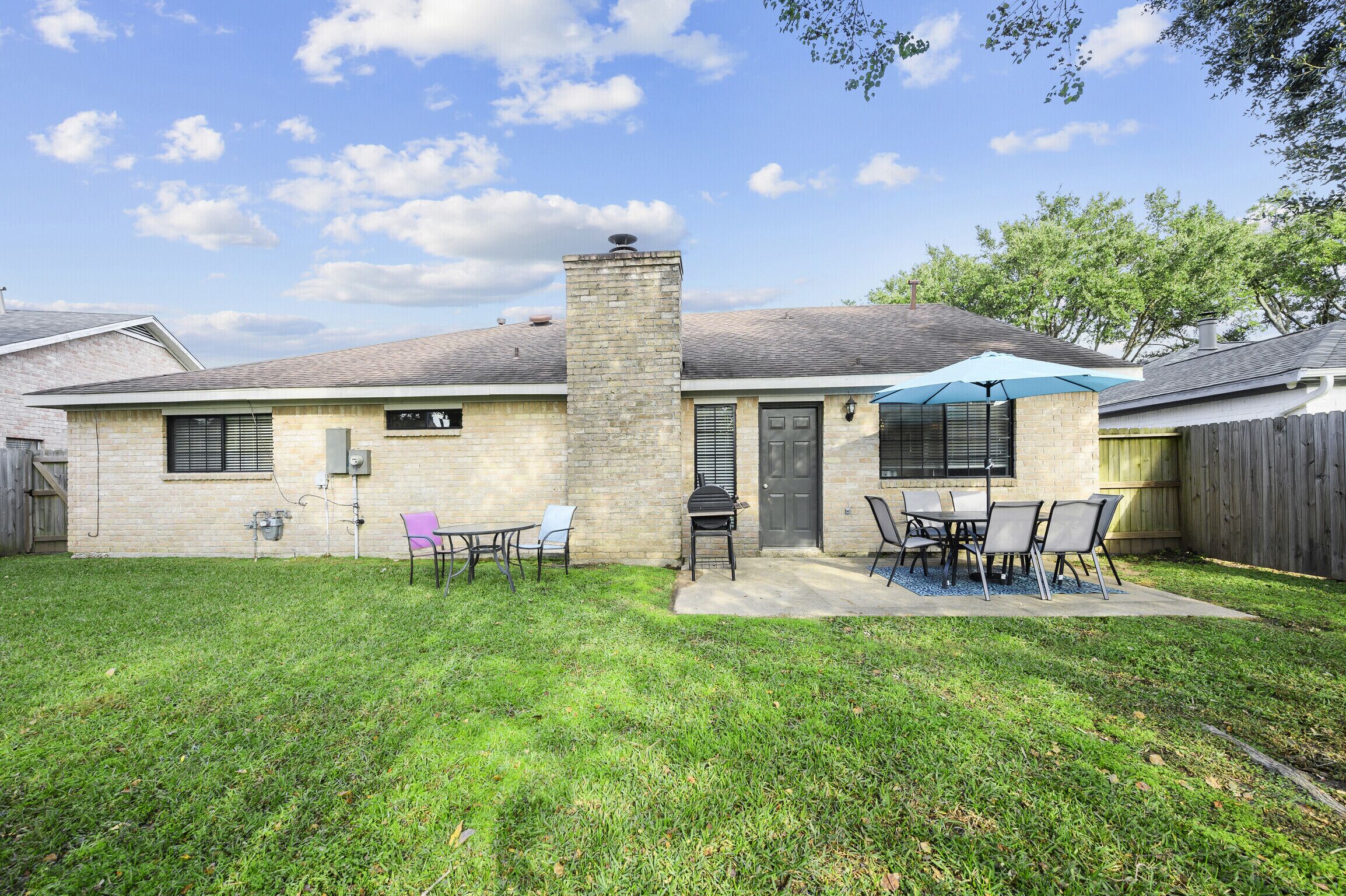 A single-story house with a brick exterior, a chimney, and a patio area with outdoor furniture.