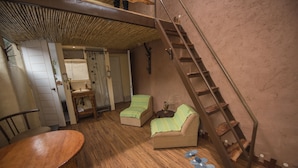 A compact room with a wooden floor, a sofa, a small table, and a staircase. - Eco Tampu - Andahuaylillas (Andahuaylillas)