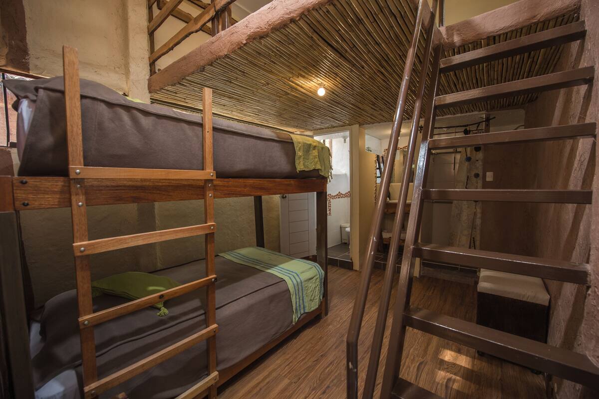 Habitación con literas, barandillas de madera y una escalera.