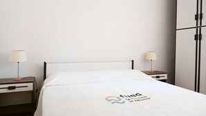 A hotel room with a bed, two bedside tables with lamps, and a wardrobe. - N040 - Numana, three-room apartment a stone's throw from the center (Numana)