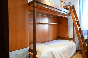 A bunk bed with a wooden frame, a ladder, and a white mattress.