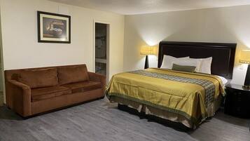 Una camera d'albergo con un letto, un divano marrone e un quadro appeso al muro.