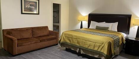 Habitación de hotel con cama, sofá marrón y un cuadro en la pared.