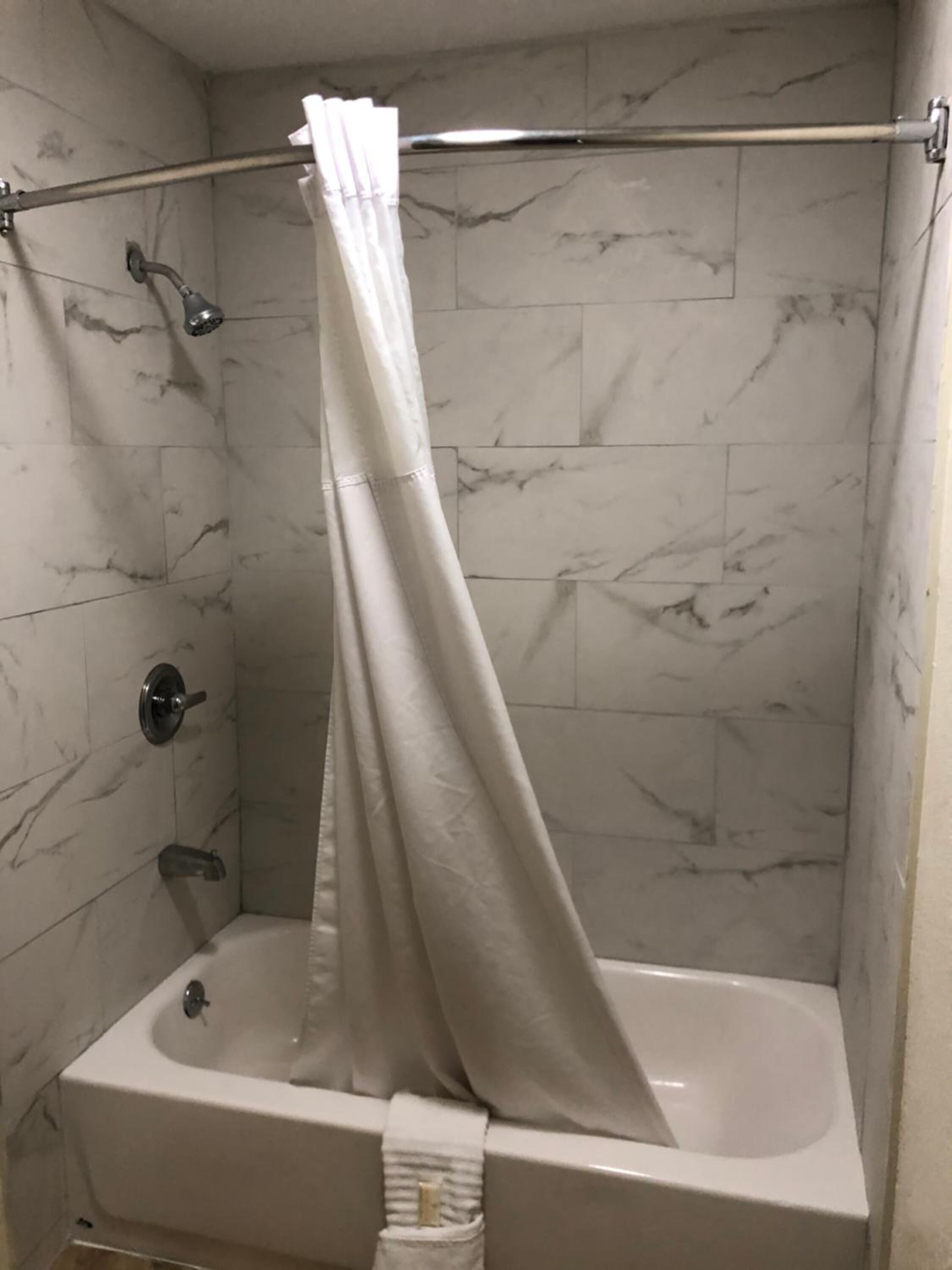 Une salle de bain avec une baignoire, un rideau de douche et un porte-serviettes.