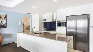 A modern kitchen with a central island, stainless steel appliances, and a view into the dining area.