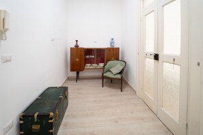 A narrow hallway with a wooden cabinet, a green armchair, and a vintage suitcase. - Monteoliveto Modern Flat by Wonderful Italy (Napoli)