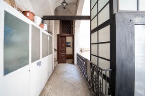 Un couloir étroit avec un sol carrelé, une porte en bois et un portail en métal.