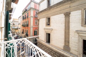 A narrow street with buildings on either side, a balcony with a metal railing, and a clear sky. - Monteoliveto Modern Flat by Wonderful Italy (Napoli)