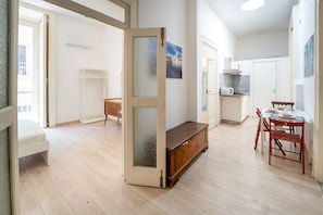 A spacious living area with a wooden bench, a dining table with chairs, and a kitchen area with a microwave. - Monteoliveto Modern Flat by Wonderful Italy (Napoli)