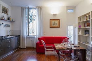 Un espacio habitable compacto con kitchenette, comedor y un sofá rojo.